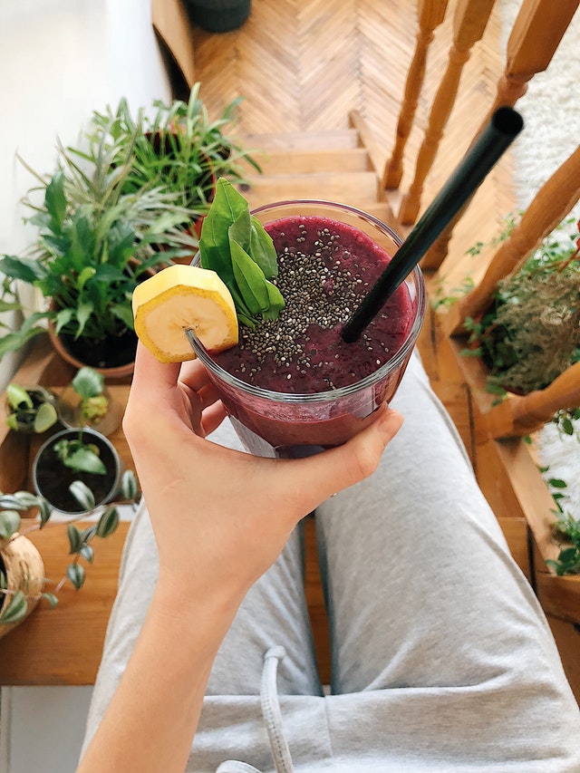 person-s-hand-holding-drinking-glass-filled-with-smoothie